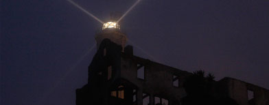 In this photo taken Thursday July 7, 2011, a lighthouse shines into the fog above the remains of the warden's house during a night tour on Alcatraz Island in San Francisco. (AP Photo/Eric Risberg)