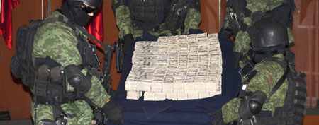 Soldiers carry a table displaying stacks of seized U.S. dollars, at a media presentation in Mexico City, Tuesday Nov. 22, 2011. (AP Photo/Eduardo Verdugo)
