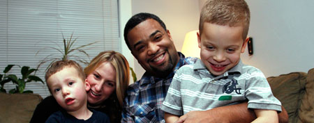 In this Dec. 27, 2011 photo, Damon Brown sits with his wife, Bethany, as they hold their sons Theo, 3, left, and Julian, 5, at their home in Seattle. (AP Photo/Elaine Thompson)