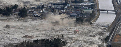 Cars and containers are swept by a tsunami wave in Miyako (AP/NHK Screengrab)