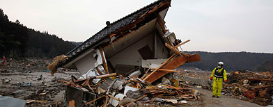 A firefighter examines the damage of a house in Saito, Miyagi Prefecture, Monday, March 14, 2011. (AP Photo/Shuji Kajiyama)