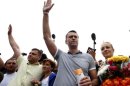 Russian protest leader Alexei Navalny and his co-defendant Pyotr Ofitserov, surrounded by supporters and journalists, gesture after arriving from Kirov at a railway station in Moscow