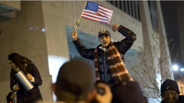 أحد أنصار أوباما يلوح بالعلم الأمريكي احتفالا بفوزه وسط حشد من المؤيدين.