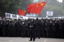 A Chinese police officer stands behind his folks confronting residents who gathered outside the government office in Zhejiang province's Ningbo city, during a protest against the proposed expansion of a petrochemical factory on Sunday, Oct. 28, 2012. Thousands of people in the eastern Chinese city clashed with police Saturday while protesting the plan that they say would spew pollution and damage public health, townspeople said. (AP Photo/Ng Han Guan)