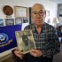 In this Nov. 29, 2011, photo, World War II Navy veteran Clarence Pfundheller poses at his Greenfield, Iowa, apartment with a photo of himself taken during basic training in 1939. Now 91, Pfundheller will be returning to Pearl Harbor on Wednesday, Dec. 7, 2011, for the 70th anniversary ceremony honoring those lost in the Dec. 7, 1941 attack that brought the United States into World War II. Accompanying him will be fellow survivors, other World War II veterans, and a handful of college students to hear their stories. (AP Photo/Charlie Neibergall)