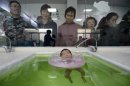 People watch an infant go through swimming exercise at a maternal and child health care hospital in Taiyuan