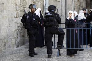 A Palestinian woman looks on as Israeli policemen prevent …