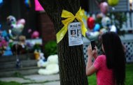 A girl takes a picture of a missing person poster showing Amanda Berry, one of the three women held captive for a decade, in front of her sister's house May 7, 2013 in Cleveland, Ohio