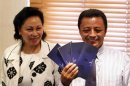 Former Madagascar leader Ravalomanana holds up air tickets standing beside his wife Lalao during a media briefing in Johannesburg