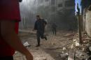 Civil Defence members run amidst debris after a strike on the rebel held besieged city of Douma, in the eastern Damascus suburb of Ghouta