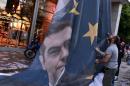 Protesters take down a huge banner bearing a picture of Greek Prime Minister Alexis Tsipras on a European Union flag from the ministry of finance in Athens as they end the occupation of the building on June 11, 2015