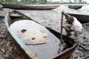 An indigene of Bodo, Ogoniland region in Rivers State, tries to separate with a stick the crude oil from water in a boat at the Bodo waterways polluted by oil spills attributed to Shell equipment failure August 11, 2011