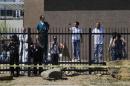 People watch from inside the fence of the Phoenix Veterans Affairs medical center as Obama's motorcade arrives, in Phoenix, Arizona