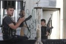 A Free Syrian Army fighter and a boy hold up weapons on a street at the Syrian town of Tel Abyad