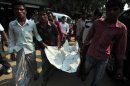 Hombres llevan cuerpos de las peronas que murieron en Bangladesh a causa deun incendio de una fábrica textil