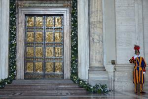 A Swiss guard stands by the "Holy Door" that …