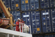 <p>               In this Oct. 18, 2011 photo, crew members look on as containers are offloaded from the cargo ship Stadt Rotenburg at Port Everglades in Fort Lauderdale, Fla. The U.S. trade deficit narrowed in October to its lowest point of the year as Americans bought fewer foreign cars and imported less oil. Exports of American-made autos also fell. (AP Photo/Wilfredo Lee)
