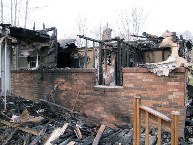This photo shows the charred remains of a home after a fire erupted, Saturday, March 9, 2013 in Gray, Ky. Fire erupted Saturday at a rural Kentucky home, killing two adults and five children inside, a coroner said. Knox County Coroner Mike Blevins said Saturday afternoon that the adult victims found inside the ranch-style home were a woman and her boyfriend. The woman was the mother of three of the children who died, while two other children were from another family, he said. (AP Photo/The Lexington Herald-Leader, Bill Estep)