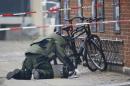 A bomb disposal expert investigates an unattended package at a cafe in Copenhagen
