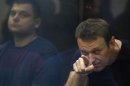 Russian protest leader Alexei Navalny and his co-defendant Pyotr Ofitserov sit in a glass-walled cage during a court session in Kirov