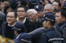 Four protest leaders, from left, Benny Tai Yiu-ting, Chan Kin-man, Joseph Zen and Chu Yiu-ming, surrounded by police officers, walk to the police station in Hong Kong as they surrender to police Wednesday, Dec. 3, 2014 to take responsibility for protests that have shut down parts of the Asian financial center for more than two months. Three founders of Hong Kong's pro-democracy protest movement called for an end to street demonstrations to prevent more violence and take the campaign to a new stage, but it wasn't clear whether student protesters, who make up the bulk of the activists, would heed the call. (AP Photo/Kin Cheung)