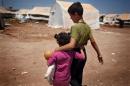 Syrian refugee children walk in the Bab al-Salam refugee camp in Syria's northern city of Azaz on July 15, 2013