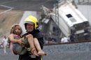 A fireman carries an injured child from the wreckage of a train crash near Santiago de Compostela