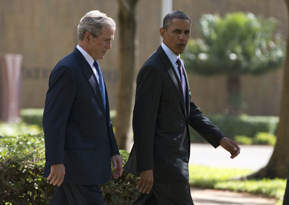 U.S. President Barack Obama, right, walks with former president George W. Bush during a wreath laying ceremony to honor the victims of the U.S. Embassy bombing on Tuesday, July 2, 2013, in Dar es Salaam, Tanzania. The president is traveling in Tanzania on the final leg of his three-country tour in Africa. (AP Photo/Evan Vucci)
