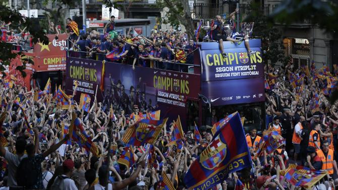Fans cheer as FC Barcelona players ride on the team bus during celebrations in Barcelona, Spain Sunday June 7, 2015 after winning the Champions League final soccer match Saturday by beating Juventus Turin 3-1. Barcelona won the triple this season winning the Spanish League title, the Copa del Rey and the Champions League. (AP Photo/Emilio Morenatti)