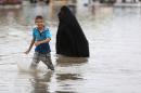 Iraqis walk through a flooded street after heavy rainfall in the capital Baghdad, on October 29, 2015