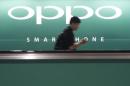 File photo of a commuter using his mobile phone passing an advertisement of Chinese smartphone maker Oppo at a train station in Singapore