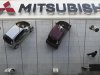 Mitsubishi Motors Corp's vehicles and a passer-by are reflected on an external wall at the company headquarters in Tokyo