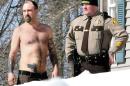 In this Tuesday, March 18, 2014 photo, Michael Smith, left, stands beside a Somerset County Sheriff deputy outside his home in Norridgewock, Maine. Officers armed with assault rifles descended on Smith's home after members of a tree removal crew he'd told to clear off his property reported that he had a gun. The "gun" the tree crew had seen on Smith actually was a life-sized tattoo of a handgun on his stomach. (AP Photo/Morning Sentinel, David Leaming)