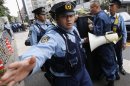 A policeman gestures at photographer as they block a protester shouting anti-China slogans in front of the Chinese Embassy in Tokyo
