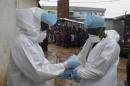 Health workers wear protective clothing before carrying an abandoned dead body presenting with Ebola symptoms at Duwala market in Monrovia