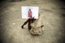 Una mujer bengalí sostiene la fotografía de su hija desaparecida, el miércoles 8 de mayo de 2013, en un depósito de cadáveres improvisado cerca del edificio que tenía fábricas de ropa y que se derrumbó en Savar, cerca de Daca, en Bangladesh. Los muertos por la tragedia sobrepasan los 800 y muchos cadáveres serán sometidos a exámenes de ADN para identificarlos por su avanzado estado de descomposición, dijeron las autoridades. (AP Foto/Ismail Ferdous)
