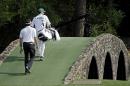 Bubba Watson walks across the Hogan Bridge with his caddie Ted Scott during the fourth round of the Masters golf tournament Sunday, April 13, 2014, in Augusta, Ga. (AP Photo/Darron Cummings)