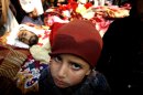 A boys sits next to his father's dead body in Peshawar, Pakistan, Wednesday, Jan. 16, 2013. Hundreds of villagers from northwest Pakistan protested Wednesday the killing of 18 of their relatives in an overnight raid that they blamed on security forces, displaying the bodies of the victims in the provincial capital. (AP Photo/Mohammad Sajjad)