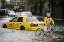 FILE - In this Aug. 28, 2011 file photo, a bicyclist makes his way past a stranded taxi on a flooded New York City street as Tropical Storm Irene passes through the city. From Cape Hatteras, N.C., to just north of Boston, sea levels are rising much faster than they are around the globe, putting one of the world's most costly coasts in danger of flooding, according to a new study published Sunday, June 24, 2012, in the journal Nature Climate Change. By the year 2100, scientists and computer models estimate that sea levels globally could rise as much as 3.3 feet. The accelerated rate along the East Coast could add about another 8 to 11 inches, Asbury Sallenger Jr., an oceanographer for the USGS said. "Where that kind of thing becomes important is during a storm," Sallenger said. That's when it can damage buildings and erode coastlines. (AP Photo/Peter Morgan, File)
