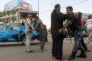 Iraqi policemen frisk Shiite Muslim pilgrims on their way to the Imam al-Kadim shrine in Baghdad on May 22, 2014