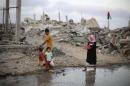Palestinians walk next to ruins of houses, which witnesses said were destroyed during Israeli offensive, on fifth day of ceasefire in Khan Younis in Gaza Strip
