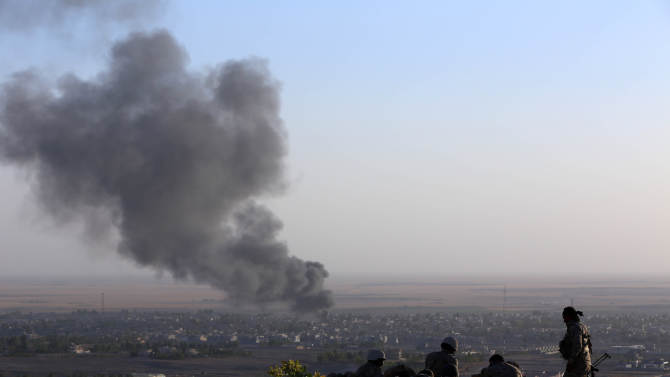 Iraqi Kurdish Peshmerga fighters look on as smoke billows from the town Makhmur during clashes with Islamic State (IS) militants on August 9, 2014