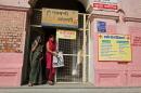 Indian women walk past a billboard advocating sterilization hung at the entrance of the District Women's Hospital in Varanasi, India, Wednesday, Nov. 12, 2014. At least a dozen women died this week following a state-run, mass sterilization program that has raised serious ethical questions about India's drive to curb a booming population by paying women to undergo tubectomies. India has one of the world's highest rates of sterilization among women, with about 37 percent undergoing such operations compared with 29 percent in China, according to 2006 statistics reported by the United Nations. About 4.6 million Indian women were sterilized in 2011 and 2012, according to the government. (AP Photo/Rajesh Kumar Singh)