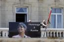 Workers hang a banner showing a portrait of Aurelie Chatelain while a black ribbon is set up around the French flag on the front of the city hall of Caudry, northern France, Wednesday, April 22, 2015. An Islamic extremist with an arsenal of loaded guns was only prevented from opening fire on churchgoers because he accidentally shot himself in the leg, French officials said Wednesday. Aurelie Chatelain, a 32-year-old Frenchwoman visiting Paris for a training session for her work, was found shot to death on Sunday morning in her car. The security official said Chatelain appeared to have been killed at random and ballistics evidence linked her death to the suspect.( AP Photo/Michel Spingler)