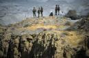 Members of Iran's Revolutionary guard personnel monitor an area as they stand on top of a hill while taking part in a war game in the Hormuz area of southern Iran