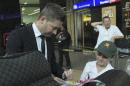 Australia's cricket captain Michael Clarke, left, signs a small cricket bat for unidentified fan during their arrival at OR Tambo International Airport in Johannesburg, South Africa, Wednesday, Jan. 29, 2013, for their Test cricket tour against South Africa. (AP Photo/ Themba Hadebe)