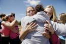 Brandi Wilson, left, and her daughter, Trisha Wilson, 15, right, embrace Trish Hall, a mother waiting for her student, as students arrived at the Fred Meyer grocery store parking lot in Wood Village, Ore., after a shooting at Reynolds High School Tuesday, June 10, 2014, in nearby Troutdale. A gunman killed a student at the high school east of Portland Tuesday and the shooter is also dead, police said. (AP Photo/Troy Wayrynen)