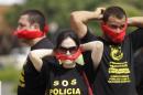 Federal police wearing T-shirts that read in Portuguese "SOS Federal Police" cover their mouths with bandanas as a way to protest their leaders' recommendation to not protest, as they demand better labor conditions outside the venue where Brazil's coach is announcing his squad for the upcoming World Cup in Rio de Janeiro, Brazil, Wednesday, May 7, 2014. Federal police are threatening to go on strike during the international soccer tournament if their demands are not met. (AP Photo/Silvia Izquierdo)
