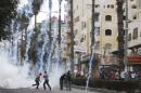 Palestinians run after Israeli troops fired tear gas canisters at protesters during clashes in the West Bank city of Hebron