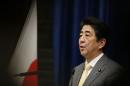 Japan's Prime Minister Shinzo Abe speaks next to the Japanese national flag, attached with a black ribbon, during a news conference in Tokyo